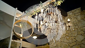 Beautiful old chandelier with crystals shines at night. Action. Romantic and old chandelier with crystals shines in open