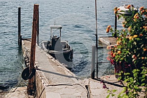 Beautiful old dock with aged wooden columns and boat on shore of Lago Maggiore on Borromean Islands near Stresa city, Italy. Pier