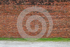 A beautiful old faded natural red brick garden wall lined with green grass