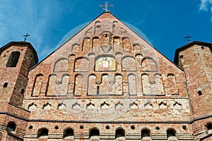 A beautiful old fortress church made of red brick against a blue sky background. A high impregnable fortress with iron crosses on