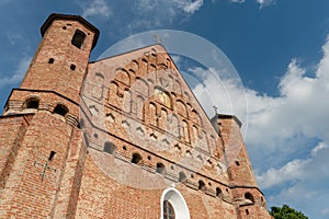 A beautiful old fortress church made of red brick against a blue sky background. A high impregnable fortress with iron crosses on