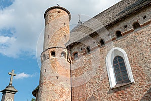 A beautiful old fortress church made of red brick against a blue sky background. A high impregnable fortress with iron crosses on