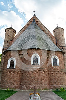 A beautiful old fortress church made of red brick against a blue sky background. Beautiful tiled roof of a medieval castle and