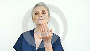 Beautiful old funny grandmother with grey hair and face with wrinkles is sending air kiss and looking at the camera on