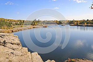 Beautiful old granite quarry with clear water in Indian summer. Chelyabinsk, Russia