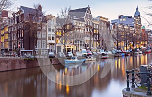 Beautiful old houses on the city embankment of Amsterdam at sunset.