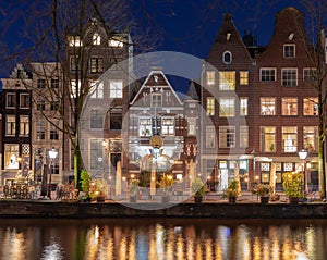 Beautiful old houses on the city waterfront of Amsterdam at sunset.