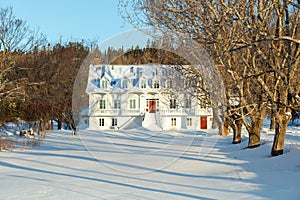 Beautiful old large white traditional French-style house with sloped metal roof and dormer windows seen in winter