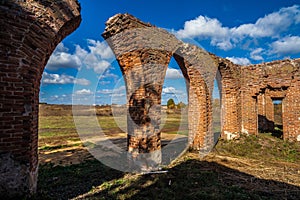 Beautiful old ruined castle of red bricks with arches at autumn on green grass background