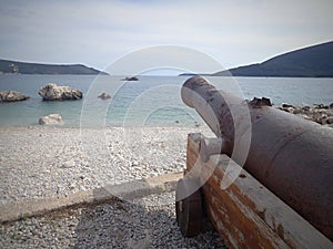 Beautiful old rusted cannon by the sea and mountains in the background