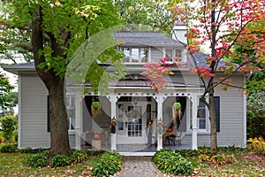 Beautiful old shingled-roofed Regency style house with Halloween display on its porch