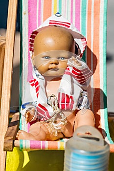 Beautiful old summer doll on small deckchair for childhood nostalgia