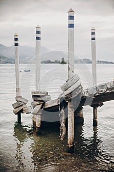 Beautiful old wooden dock with aged columns in white and blue colors on shore of Lago Maggiore in Stresa city, Italy. Pier on Lago