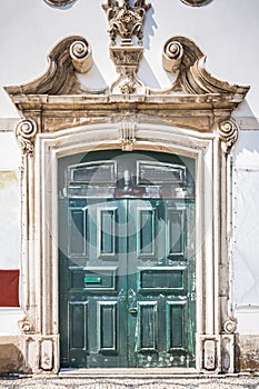 Beautiful old wooden door with stone door platband and ornate ornament. Old paneled green wooden door in the old building