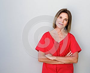 Beautiful older woman with arms crossed against gray background