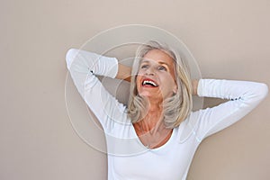 Beautiful older woman leaning with hands behind head