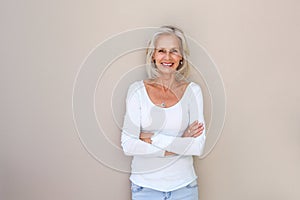 Beautiful older woman standing and smiling with arms crossed