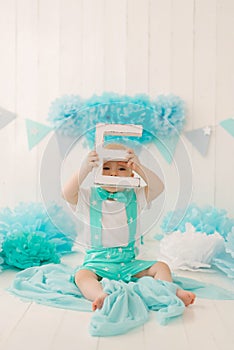 A beautiful one-year-old boy in turquoise clothes plays with the