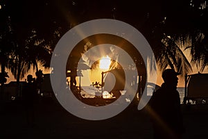 Beautiful orange beach dusk scene with palms and people silhouette