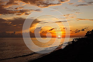 Beautiful orange sky illuminated by the sunset with a beach in the foreground in Amed, Bali