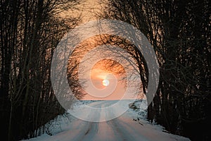 Orange sunset on countryside snowy road