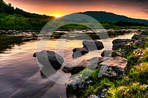 beautiful orange sunrise river landscape with stone around it