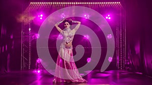 Beautiful oriental belly dancer is dancing and demonstrating the flexibility and attractiveness of her body. Purple