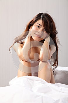 Beautiful oriental girl smiling sitting in bed