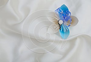 Beautiful origami flower on a white shiny textile background