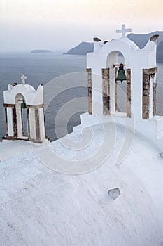 Arch with a bell, white houses and church with blue domes in Oia or Ia at golden sunset, island Santorini, Greece. - Immagine photo