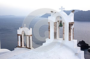 Arch with a bell, white houses and church with blue domes in Oia or Ia at golden sunset, island Santorini, Greece. - Immagine photo