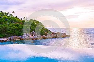 Beautiful outdoor infinity swimming pool in hotel resort with sea ocean view and white cloud blue sky