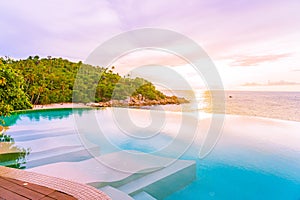 Beautiful outdoor infinity swimming pool in hotel resort with sea ocean view and white cloud blue sky