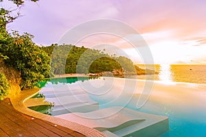 Beautiful outdoor infinity swimming pool in hotel resort with sea ocean view and white cloud blue sky