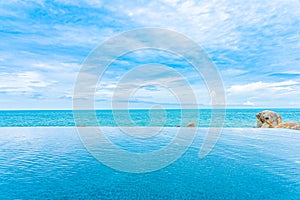 Beautiful outdoor infinity swimming pool in hotel resort with sea ocean view and white cloud blue sky