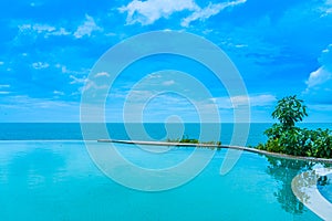 Beautiful outdoor infinity swimming pool in hotel resort with sea ocean view and white cloud blue sky