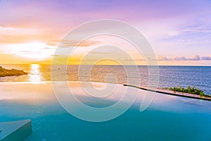 Beautiful outdoor infinity swimming pool in hotel resort with sea ocean view and white cloud blue sky