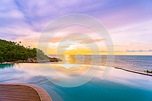 Beautiful outdoor infinity swimming pool in hotel resort with sea ocean view and white cloud blue sky