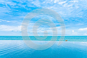 Beautiful outdoor infinity swimming pool in hotel resort with sea ocean view and white cloud blue sky