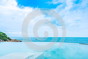 Beautiful outdoor infinity swimming pool in hotel resort with sea ocean view and white cloud blue sky