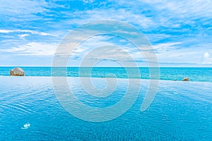 Beautiful outdoor infinity swimming pool in hotel resort with sea ocean view and white cloud blue sky