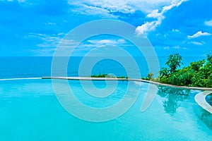 Beautiful outdoor infinity swimming pool in hotel resort with sea ocean view and white cloud blue sky