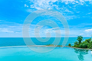 Beautiful outdoor infinity swimming pool in hotel resort with sea ocean view and white cloud blue sky