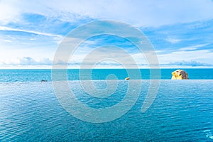 Beautiful outdoor infinity swimming pool in hotel resort with sea ocean view and white cloud blue sky