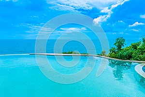 Beautiful outdoor infinity swimming pool in hotel resort with sea ocean view and white cloud blue sky