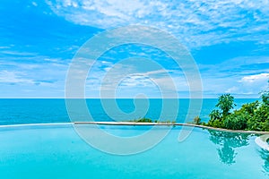 Beautiful outdoor infinity swimming pool in hotel resort with sea ocean view and white cloud blue sky