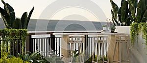 A beautiful outdoor relaxation space on a balcony with green tropical plants, a table with stools