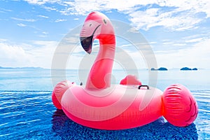 Beautiful outdoor swimming pool in hotel resort with flamingo float around sea ocean white cloud on blue sky