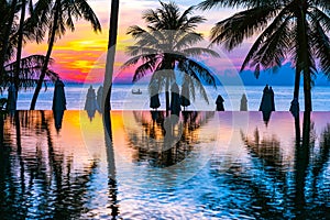 Beautiful outdoor tropical nature landscape of swimming pool in hotel resort with coconut palm tree umbrella and chair nearly sea