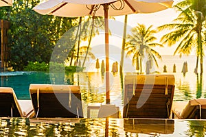 Beautiful outdoor tropical nature landscape of swimming pool in hotel resort with coconut palm tree umbrella and chair nearly sea